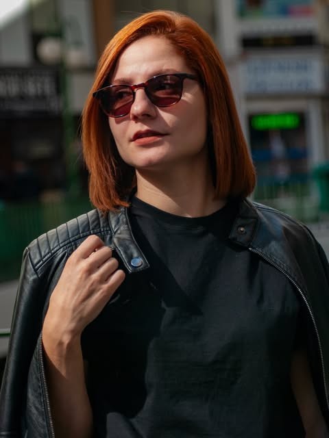 Retrato em cor de mulher ruiva de óculos escuros e jaqueta de couro